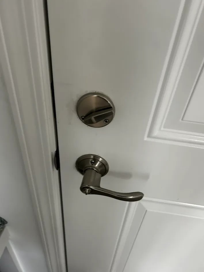 The interior face of the finished door with the deadbolt thumb turn above a brushed steel lever handle