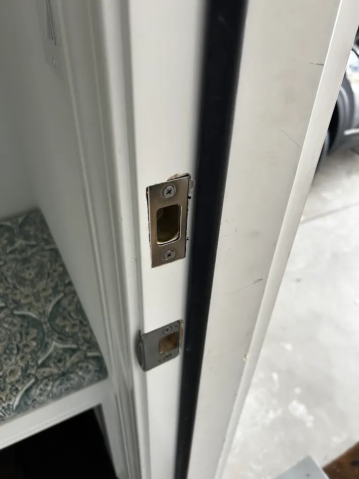 The finished door edge with the steel strike plate and latch plate fitted to the frame
