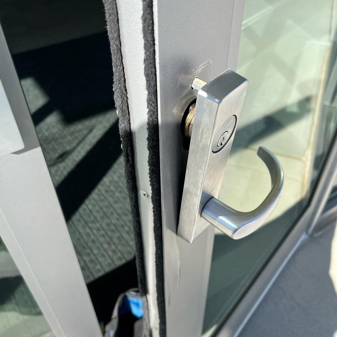 Silver lever handle with round push button lock on aluminum glass door