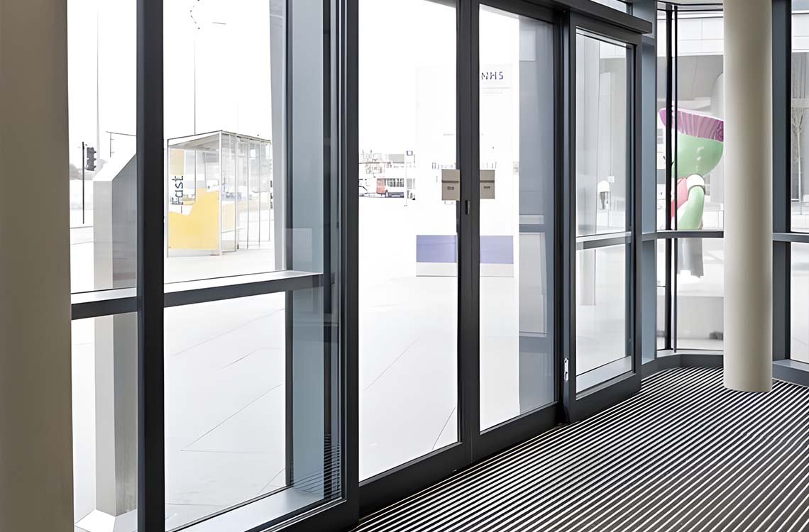 Glass storefront doors and windows with dark frames above a striped floor